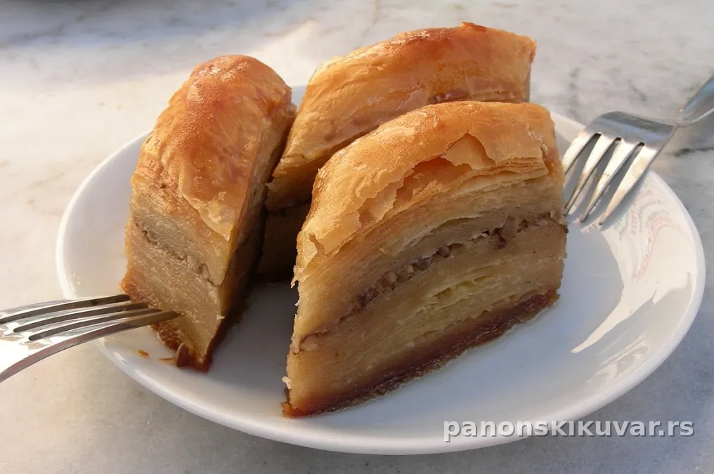zlatna baklava isecena na romboide sa vidljivim slojevima oraha i griza