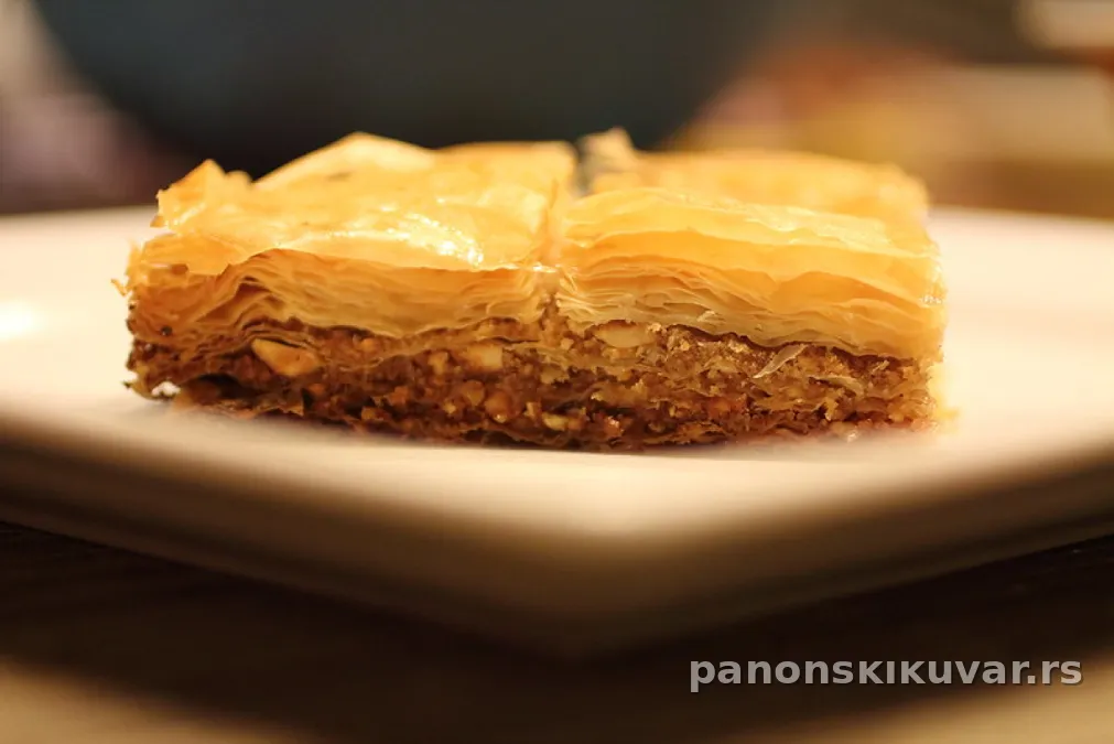 komad baklave sa kikirikijem preliven tankim sjajnim sirupom i posut mlevenim orasima