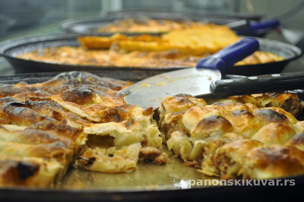 zlatno-braon burek presečen na parče, vidi se fil od mesa i šampinjona