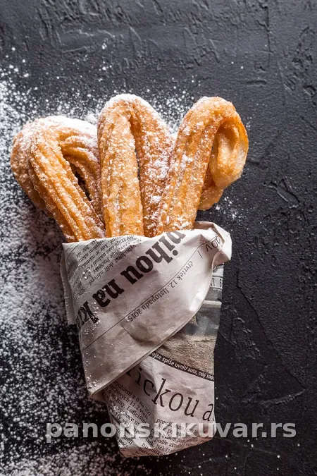zlatni prženi churros štapići uvaljani u šećer i cimet, posluženi topli