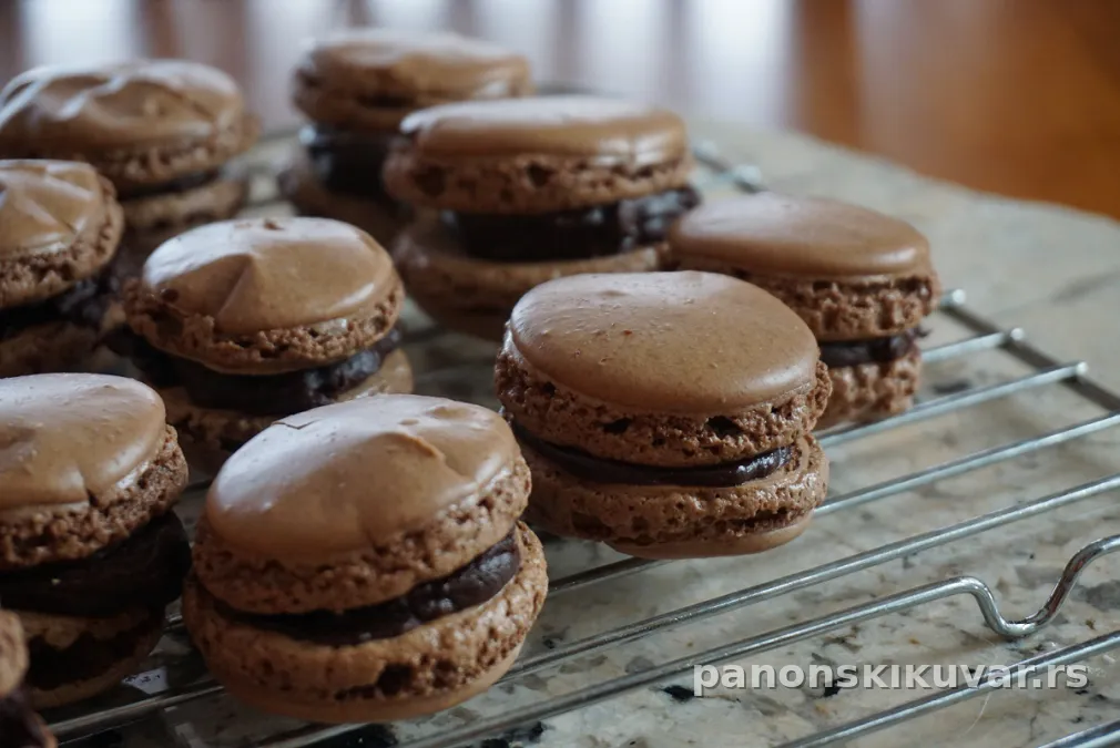 tamni čoko macaroons sa čokoladnim nadevom, poređani na tanjiru uz šolju kafe
