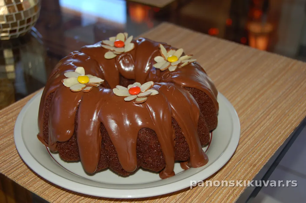 sočan čokoladni kuglof sa sjajnom čokoladnom glazurom, isečeno parče, posluženo uz šolju kafe