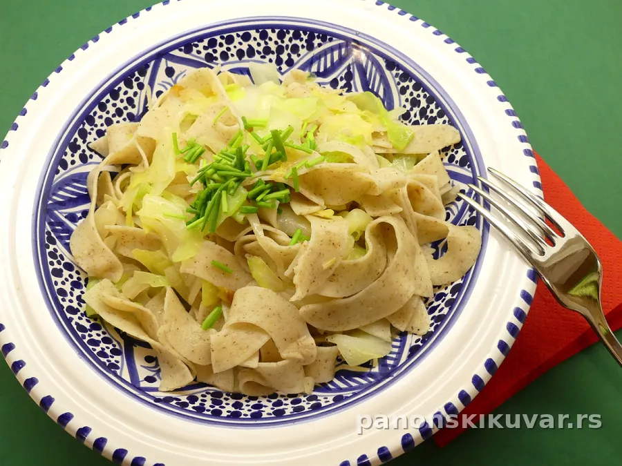 poredjani domaći tagliatelle pomešani sa rumenim prženim slatkim kupusom u beloj činiji posuto biberom