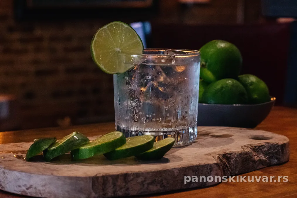 visoka čaša gin tonica sa ledom, kriškom limete i vidnim mehurićima tonika