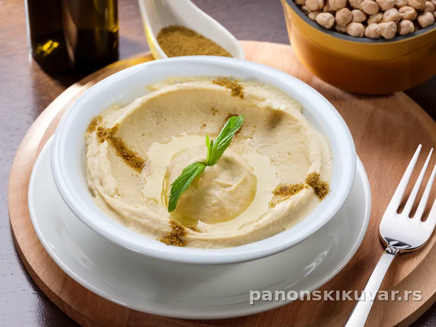 kremasti humus na tanjiru ukrašen maslinovim uljem i peršunom
