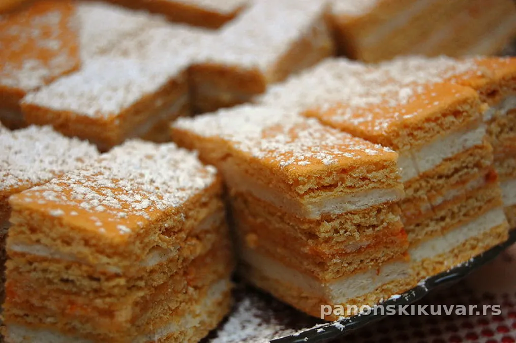 medena torta sa slojevima i orasima presečena i posuta prah šećerom