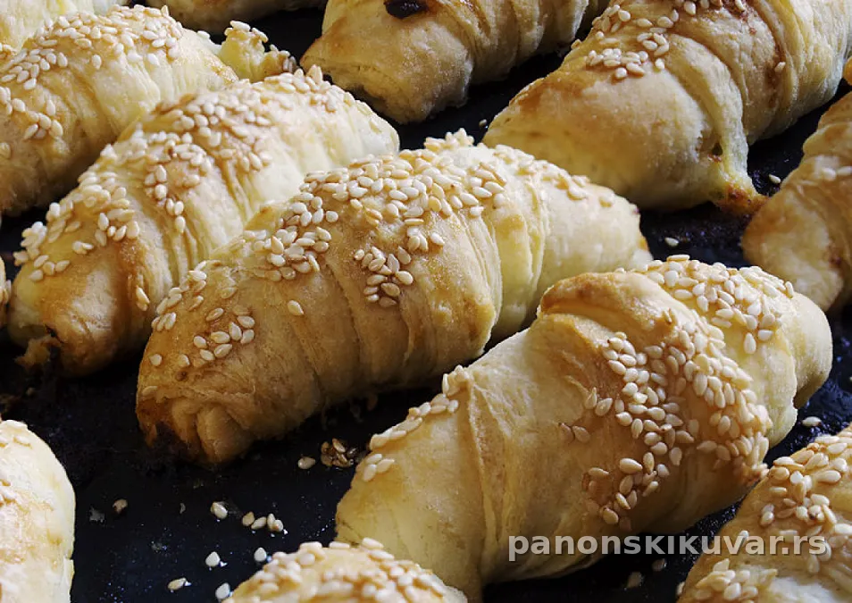Zlatno-smeđe mekane kiflice posute susamom, poređane na plehu spremne za posluženje