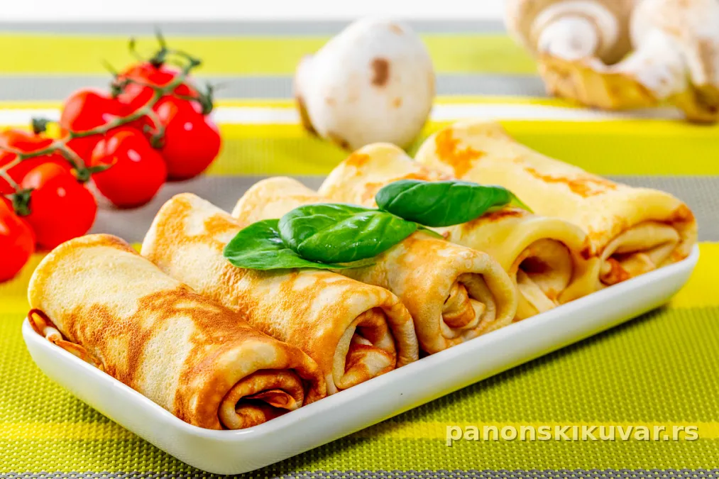 palačinke punjene pečurkama sa zlatno prženim lukom i peršunom na tanjiru