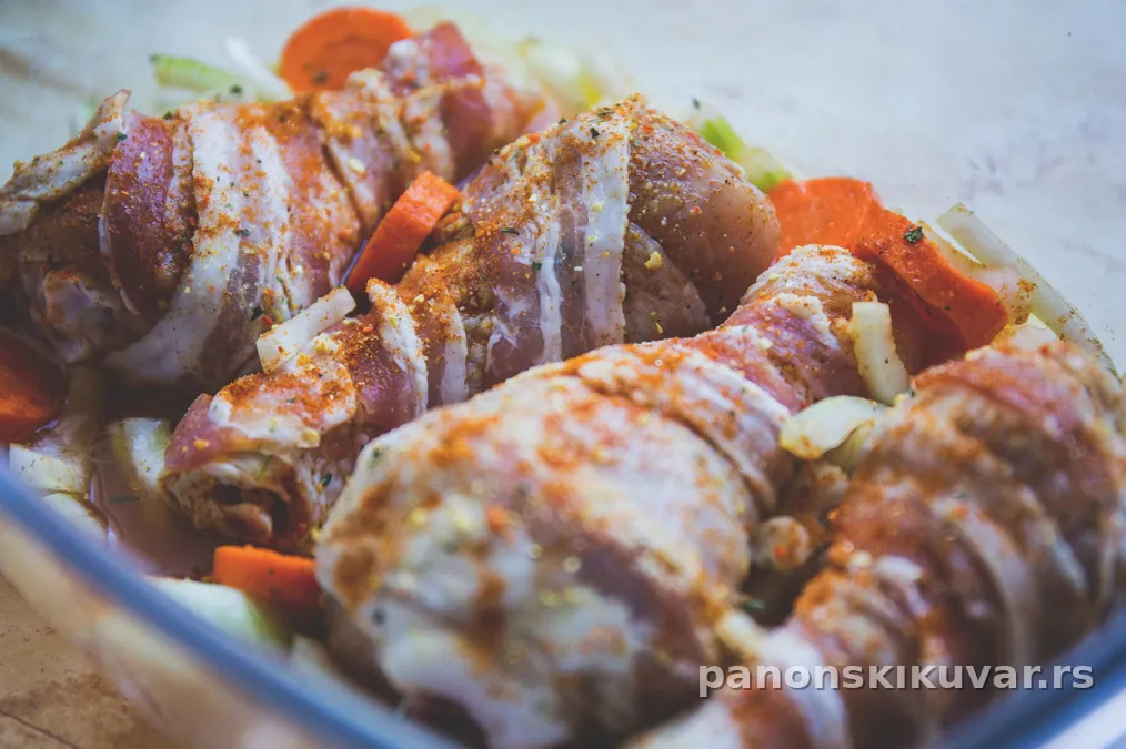 pečeni bataci uvijeni u slaninu na sloju luka i šargarepe