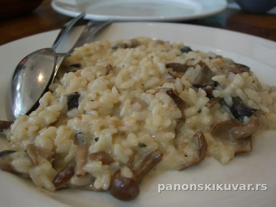 Topao tanjir pirinča sa zlatno-dinstanim pečurkama, posutim parmezanom i peršunom