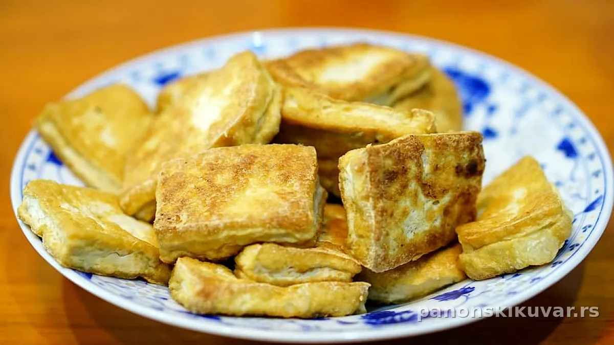 zlatno-smeđi prženi tofu u kukuruznoj kaši posluženo uz povrće na pari