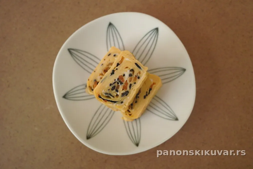 rolovani omlet isečen na dve šnite posut peršunom uz paradajz i pavlaku