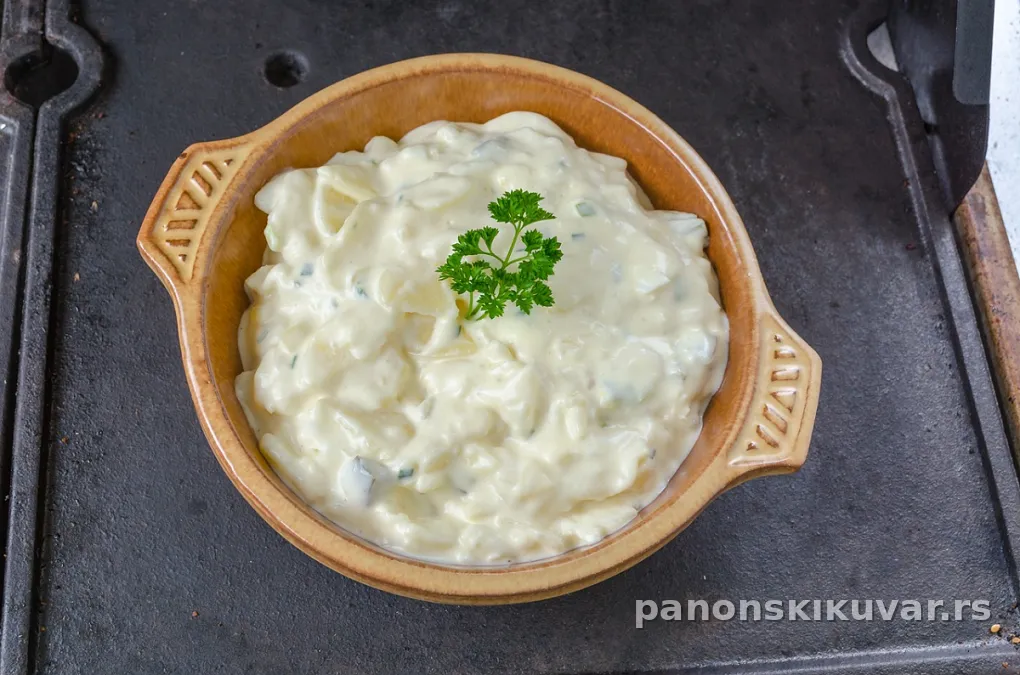 zdjela sa kremastom salatom od piletine, komadi šunke i kapar na vrhu