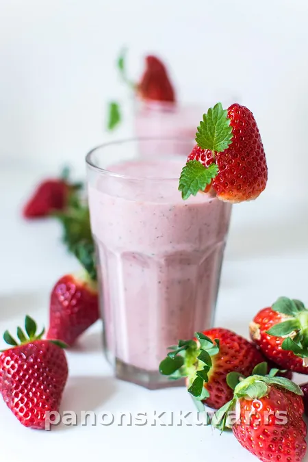 Čaša ružičastog smoothija sa listićima sveže mente i koricom limuna