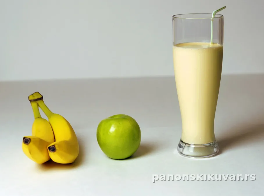 čaša kremastog smoothieja sa bananom i jabukom na drvenom stolu, posluženo