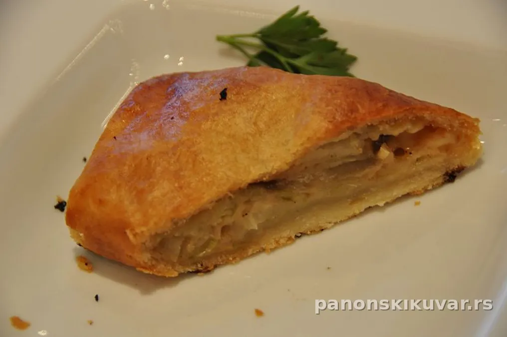 dve zlatnopečene štrudle sa sirom presečene, vidljiv kremasti nadev, na drvenoj dasci