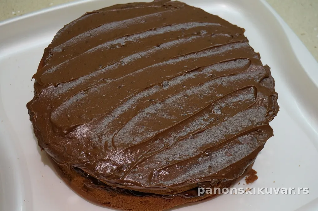 torta sa sjajnom tamnom čokoladnom glazurom i presečenim slojevima filovanih oraha